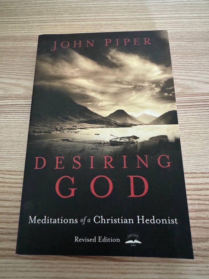 ジョン・パイパー『Desiring God』改訂版の表紙。暗い空と山あいの湖、岸に引き上げられた小舟の写真の上に赤い文字でタイトルが入っている