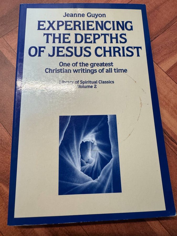 ジャンヌ・ギヨン『EXPERIENCING THE DEPTHS OF JESUS CHRIST』の青い表紙。木の床に置かれたペーパーバック